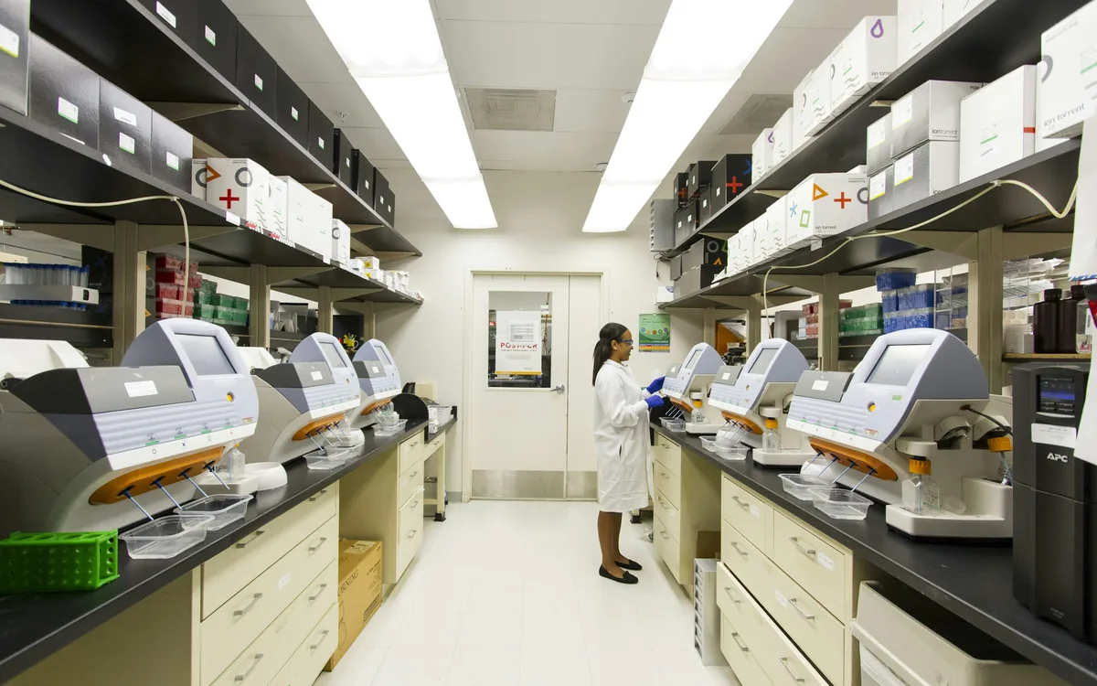Technician working among rows of bench-top genomic sequencing instruments
