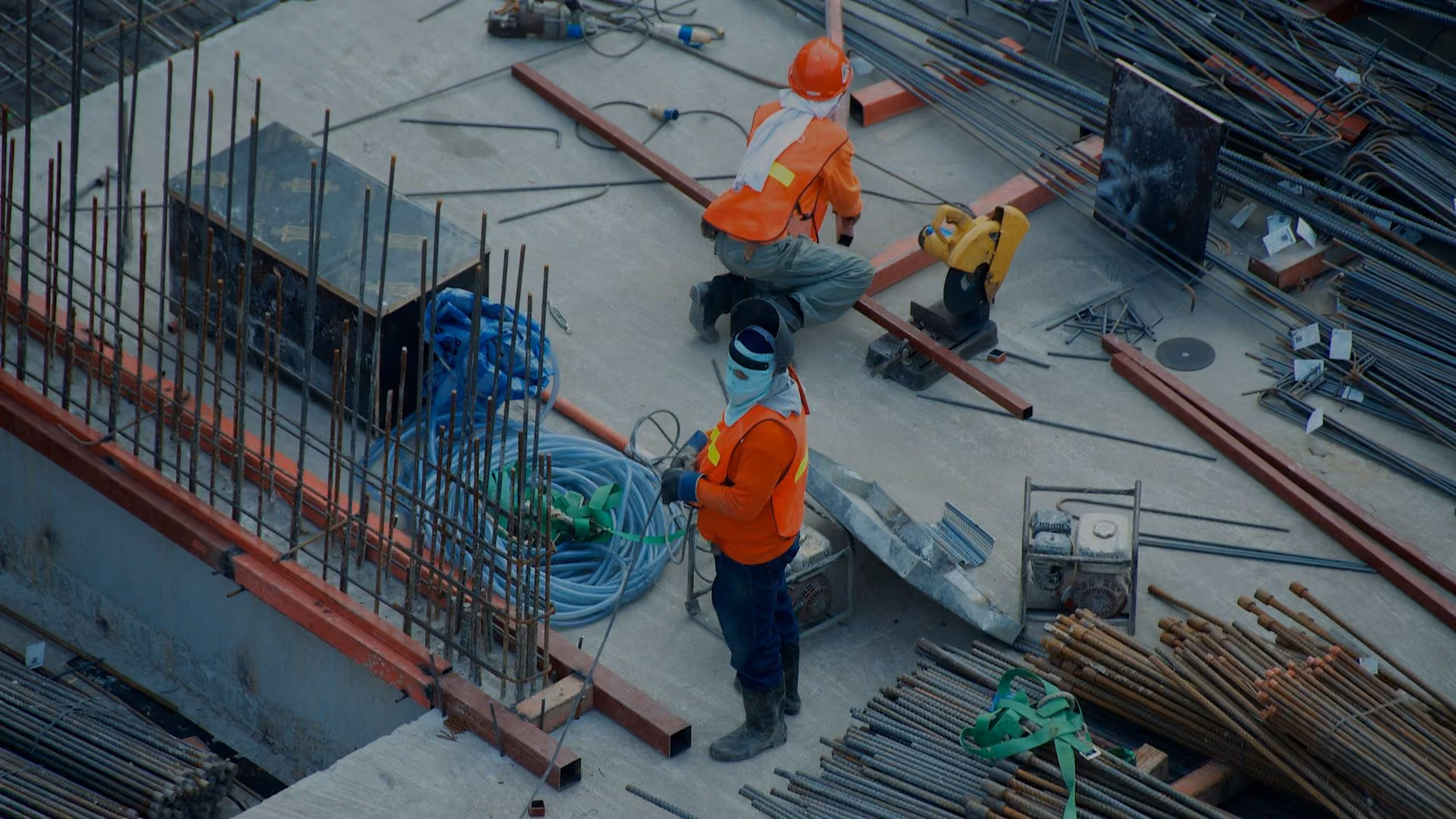 Construction workers in high-visibility PPE on a rebar deck