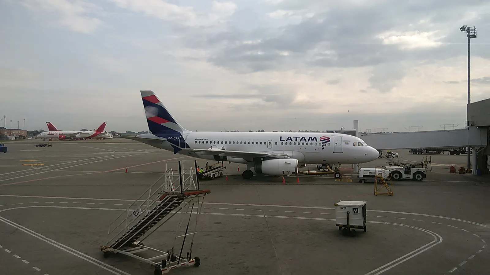 An airliner waits at a jet bridge at Alfonso Bonilla Aragón International Airport in Cali, Colombia, with a second jet parked beyond; boxes mark both aircraft and 2 ground crew.