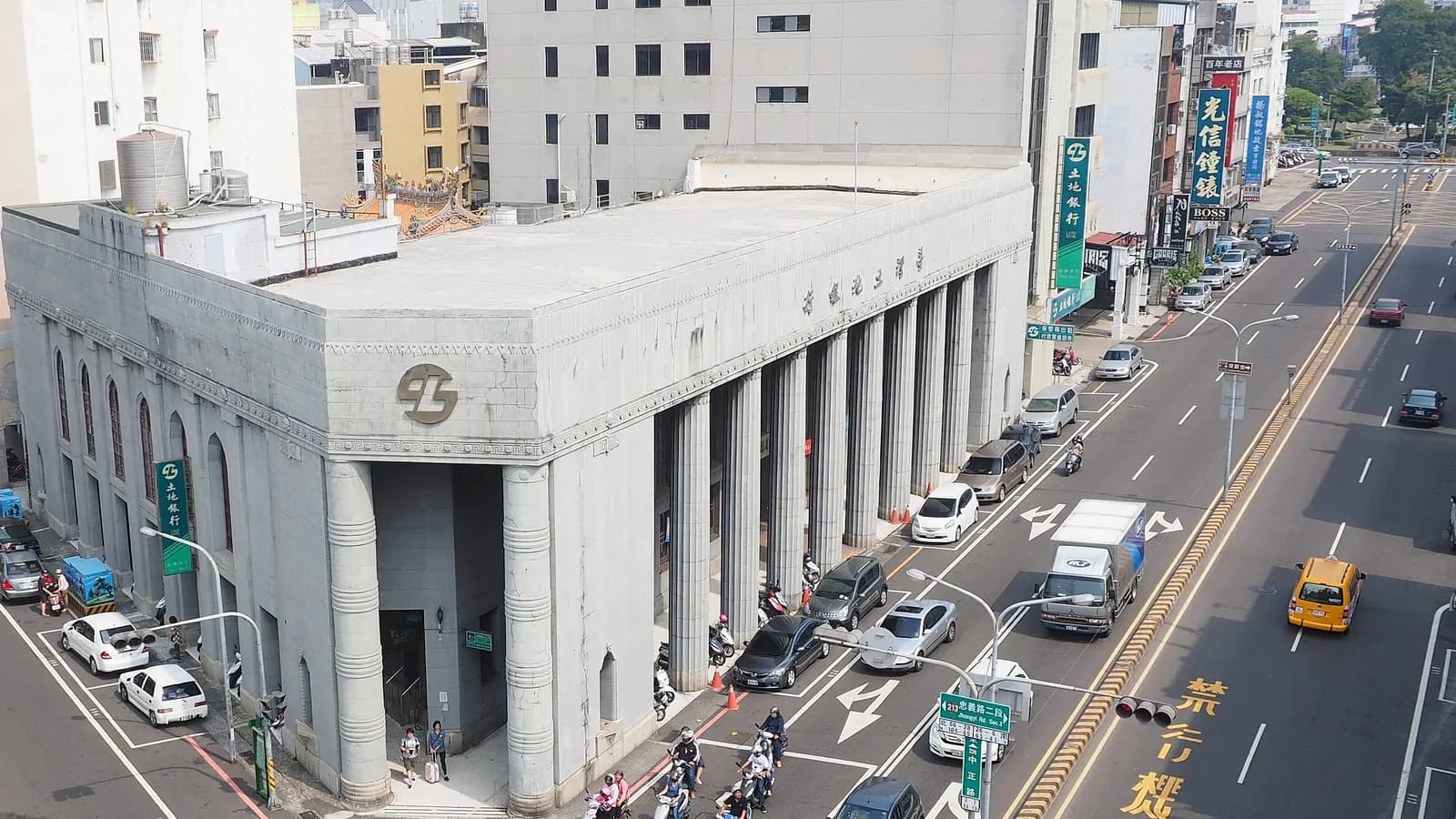 Scooter riders and pedestrians pass the columned Land Bank of Taiwan branch in Tainan, seen from a building across the street; boxes mark 12 people.