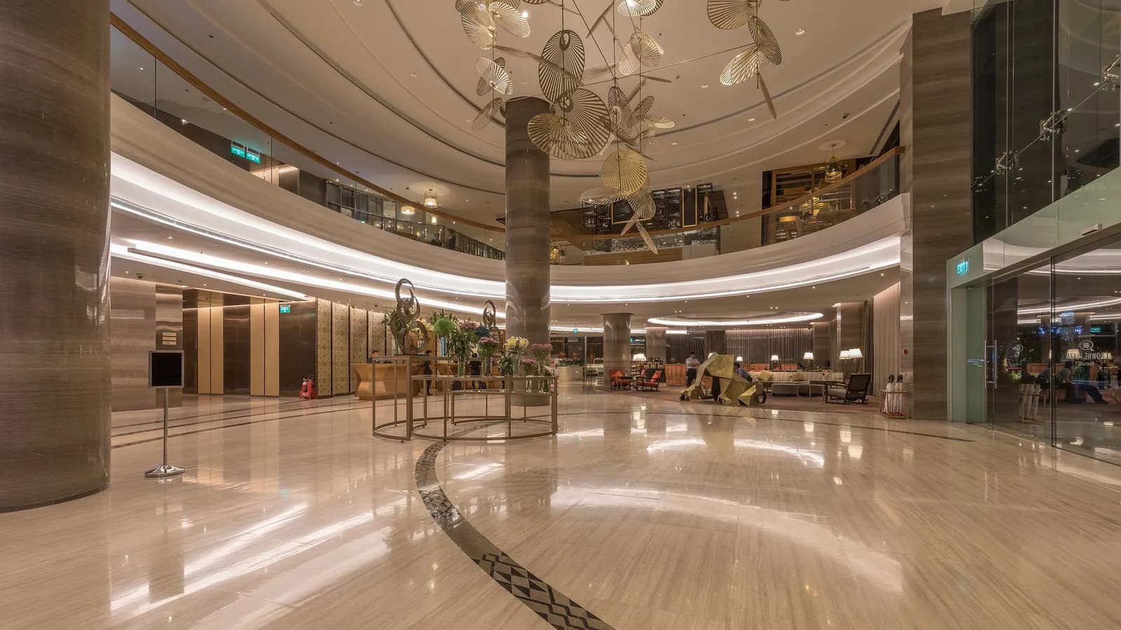 A round marble hotel lobby with a large sculpture and lounge seating; boxes mark 2 chairs and 2 people.