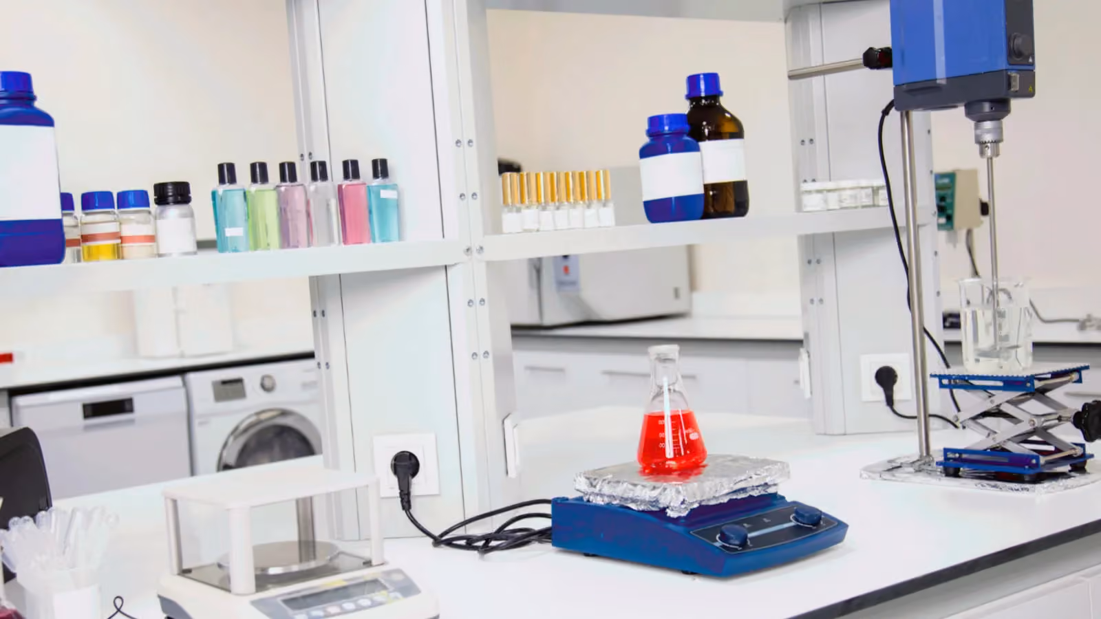 Reagent bottles line the shelves of a biotech lab above a stirrer and a flask of red liquid; boxes mark thirteen bottles.
