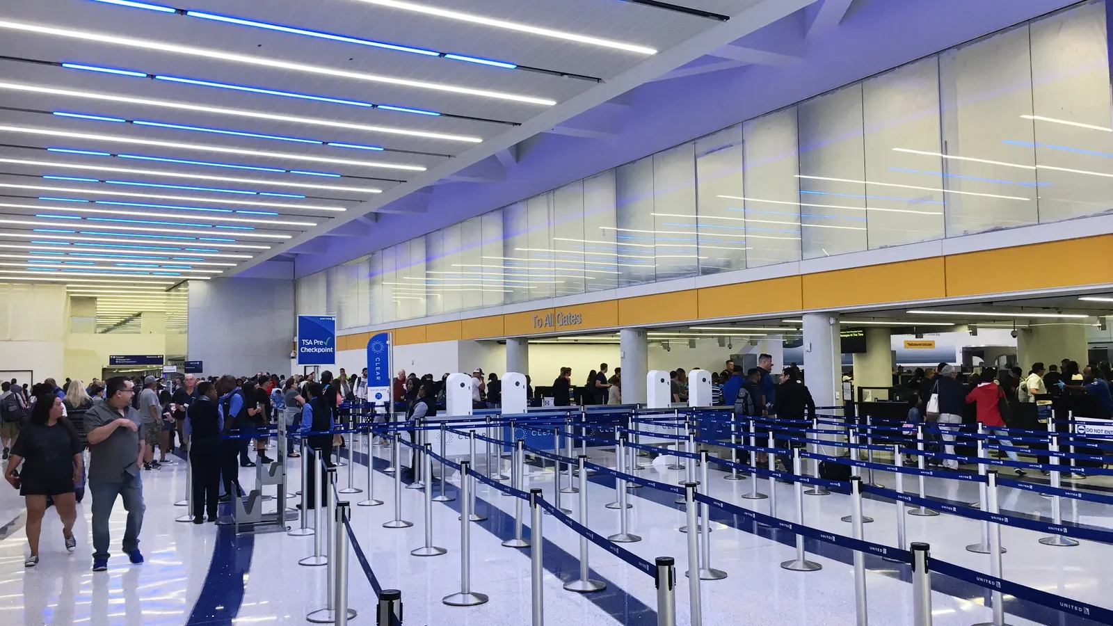 Passengers walk through rows of queue lanes toward the screening area of a central checkpoint at Los Angeles International Airport; boxes mark 18 people, 2 backpacks and 2 bags.
