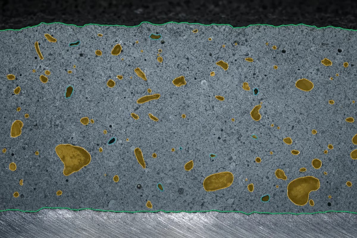 Synthetic coating cross-section with an ROI boundary and highlighted pores of varied sizes