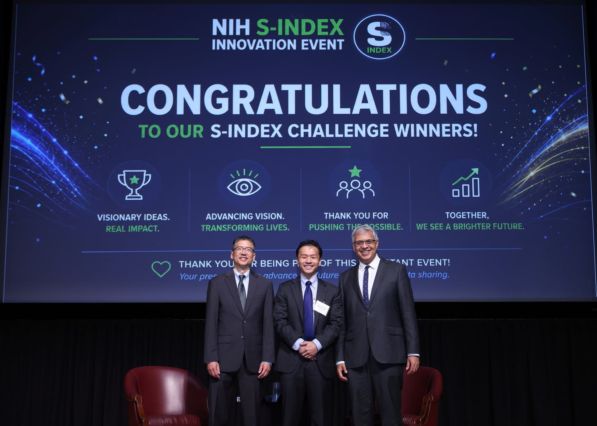 Shuhan He standing with NIH leaders on stage beneath a screen congratulating the S-Index Challenge winners