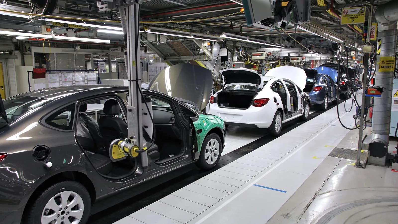 Car bodies without doors move along a modern assembly line; boxes mark 3 cars.