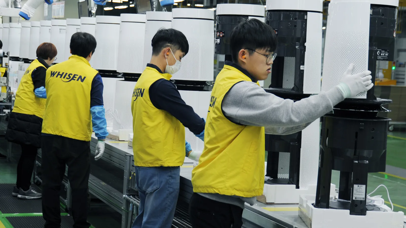 Four workers in yellow vests assemble air purifiers on a production line; boxes mark each worker and one face mask.