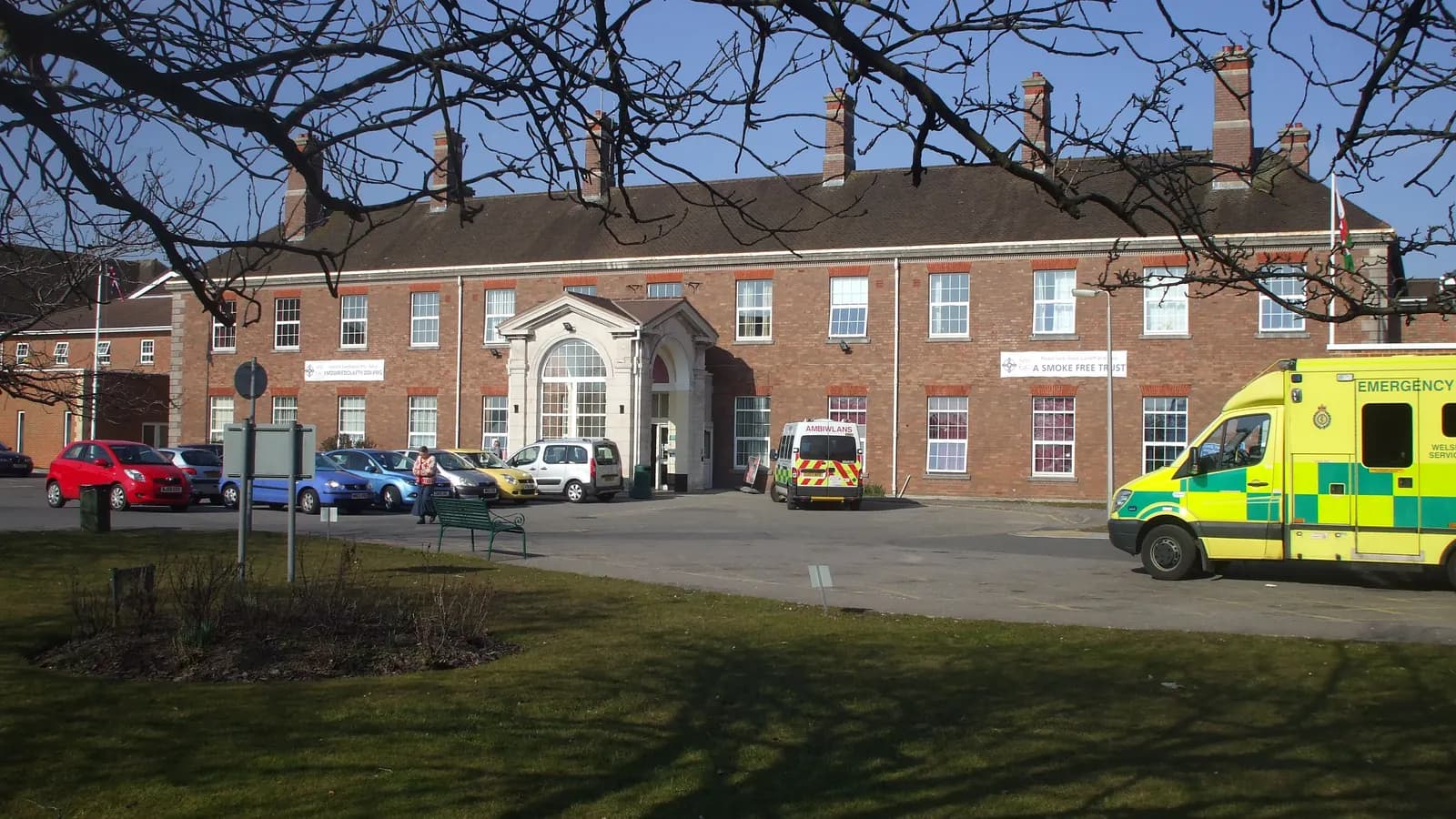 Parked cars and two ambulances outside the main entrance of Llandough Hospital in Wales; boxes mark 7 cars, 2 people and both ambulances.