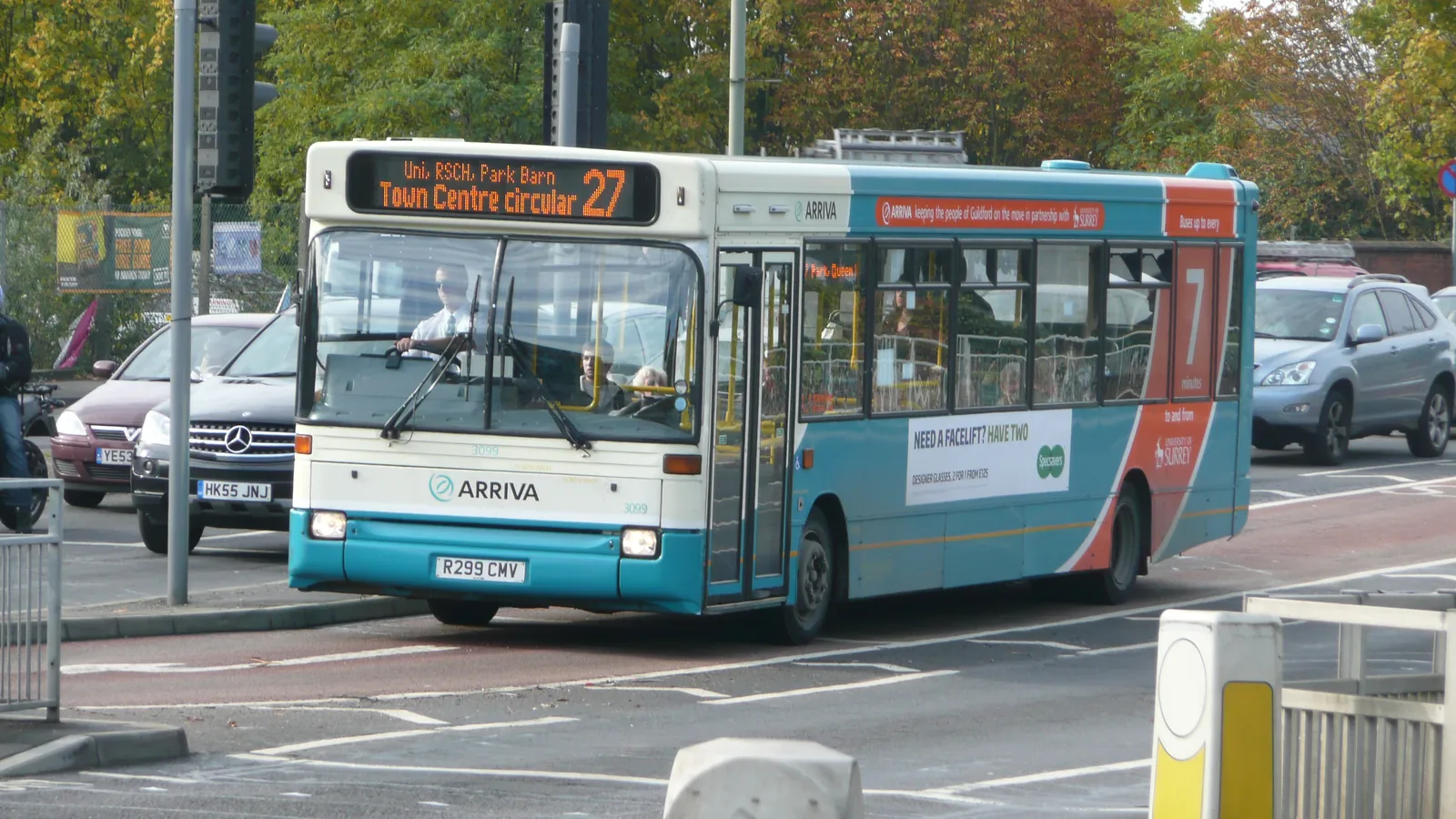 A bus pulls through a town junction past waiting cars; boxes mark the bus, four cars and three license plates.