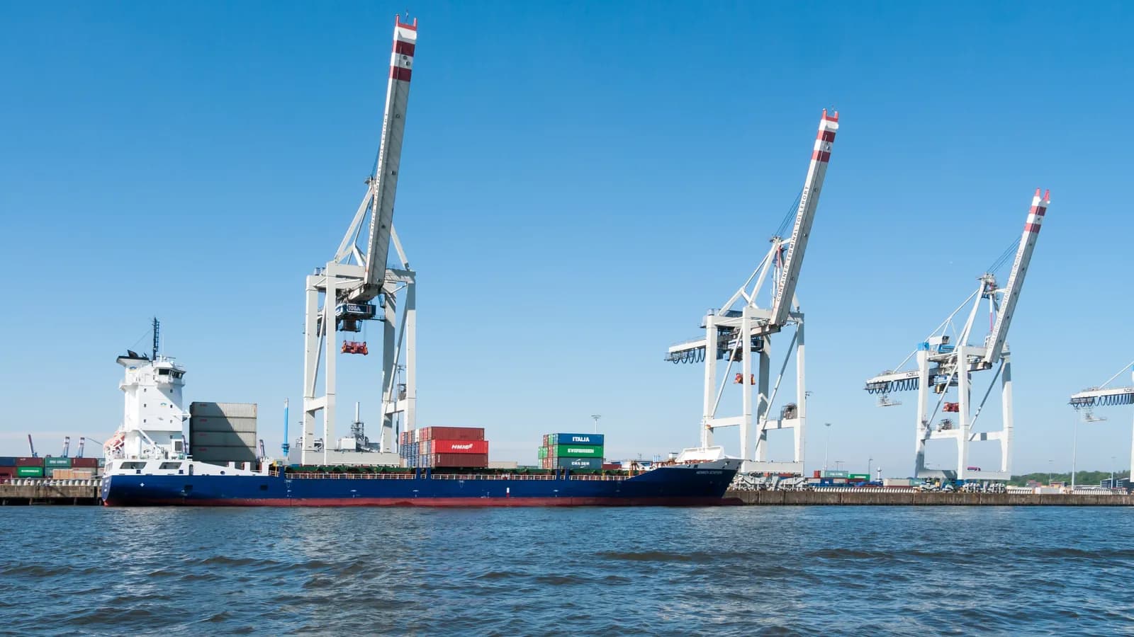 Quay cranes stand over a container terminal in Hamburg with a small container ship in the foreground; boxes mark 3 gantry cranes.