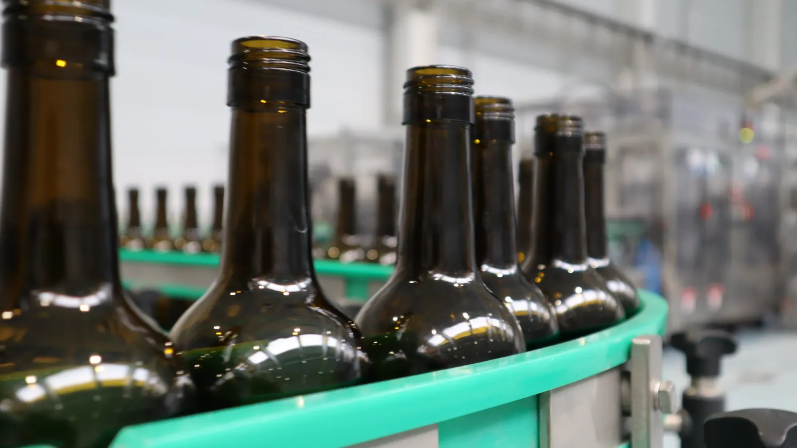 Empty wine bottles move around a curved guide on a bottling line; boxes mark 7 bottles.