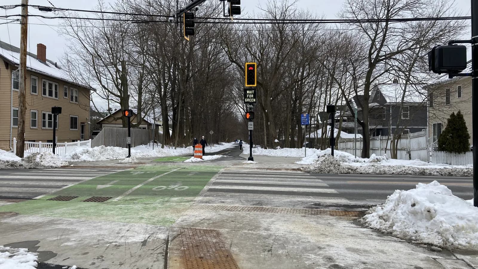 Signals control a bike path crossing on a snowy street; boxes mark 6 traffic lights and 5 people on the path.
