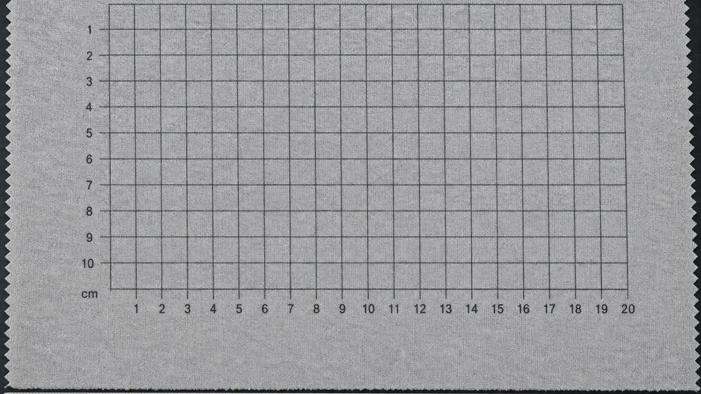 Knitted fabric laid flat with a printed measurement grid and a ruler, the layout used to measure shrinkage and skew before and after washing